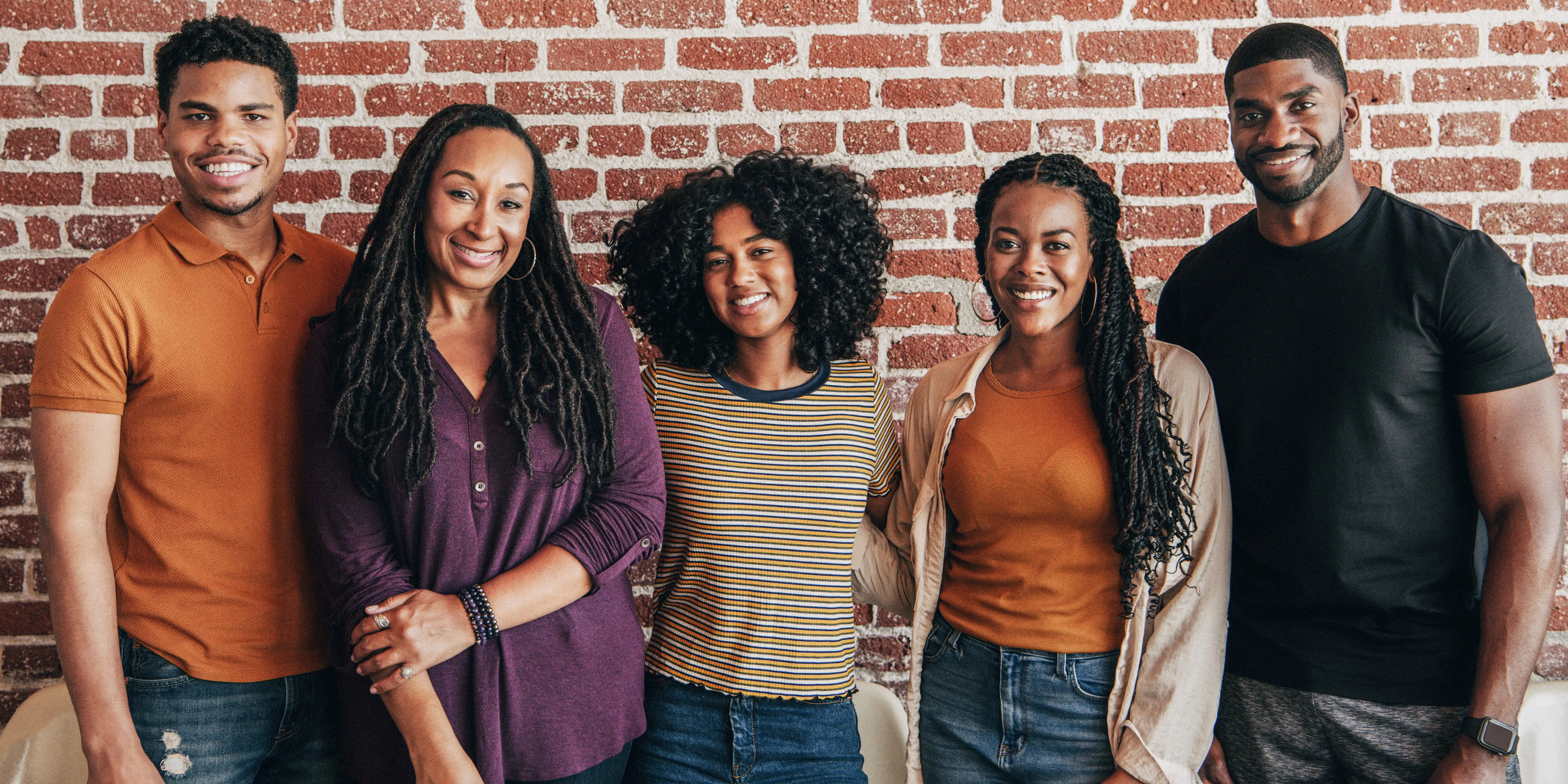 cheerful black people standing front red brick wall
